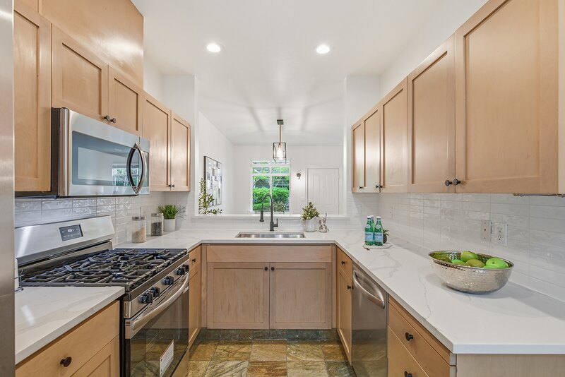 Kitchen with light wood cabinets, white countertops and a Zellige-style tile backsplash