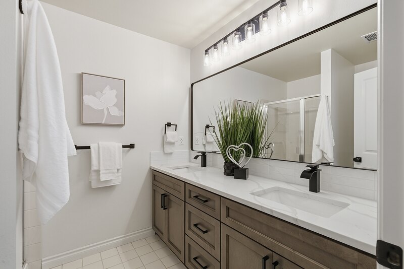 Primary bathroom double vanity with a large framed mirror