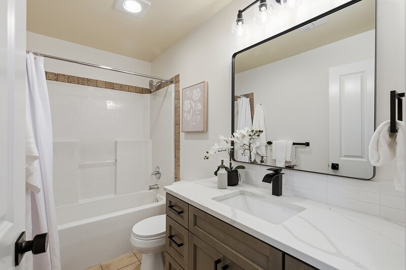 Hall bathroom with a new vanity, framed mirror and tub-shower